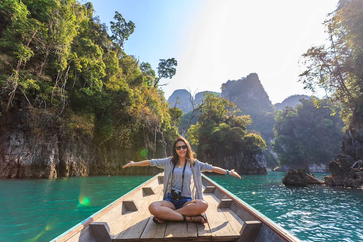 A traveler on a longtail boat between jungle cliffs